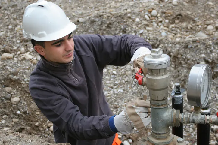 A man in a hard hat fixing pipes